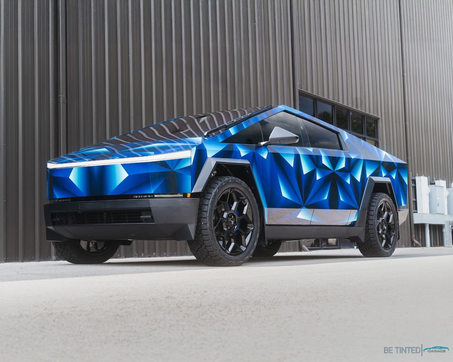 Tesla Cybertruck in a custom geometric blue wrap, front three-quarter