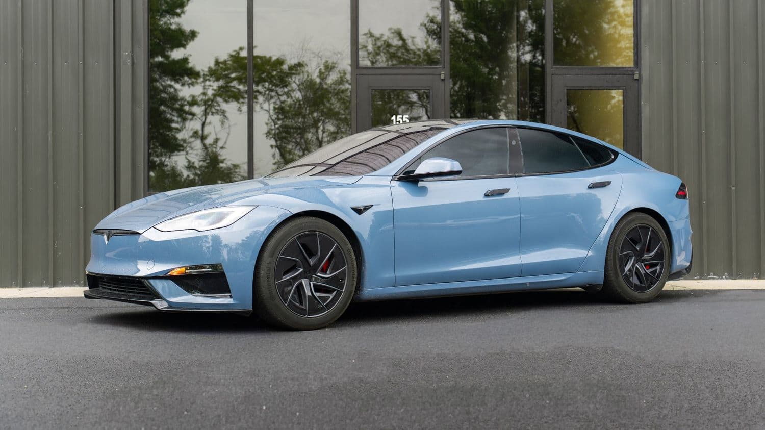 Flat blue Tesla Model S Plaid side profile outside the Be Tinted studio